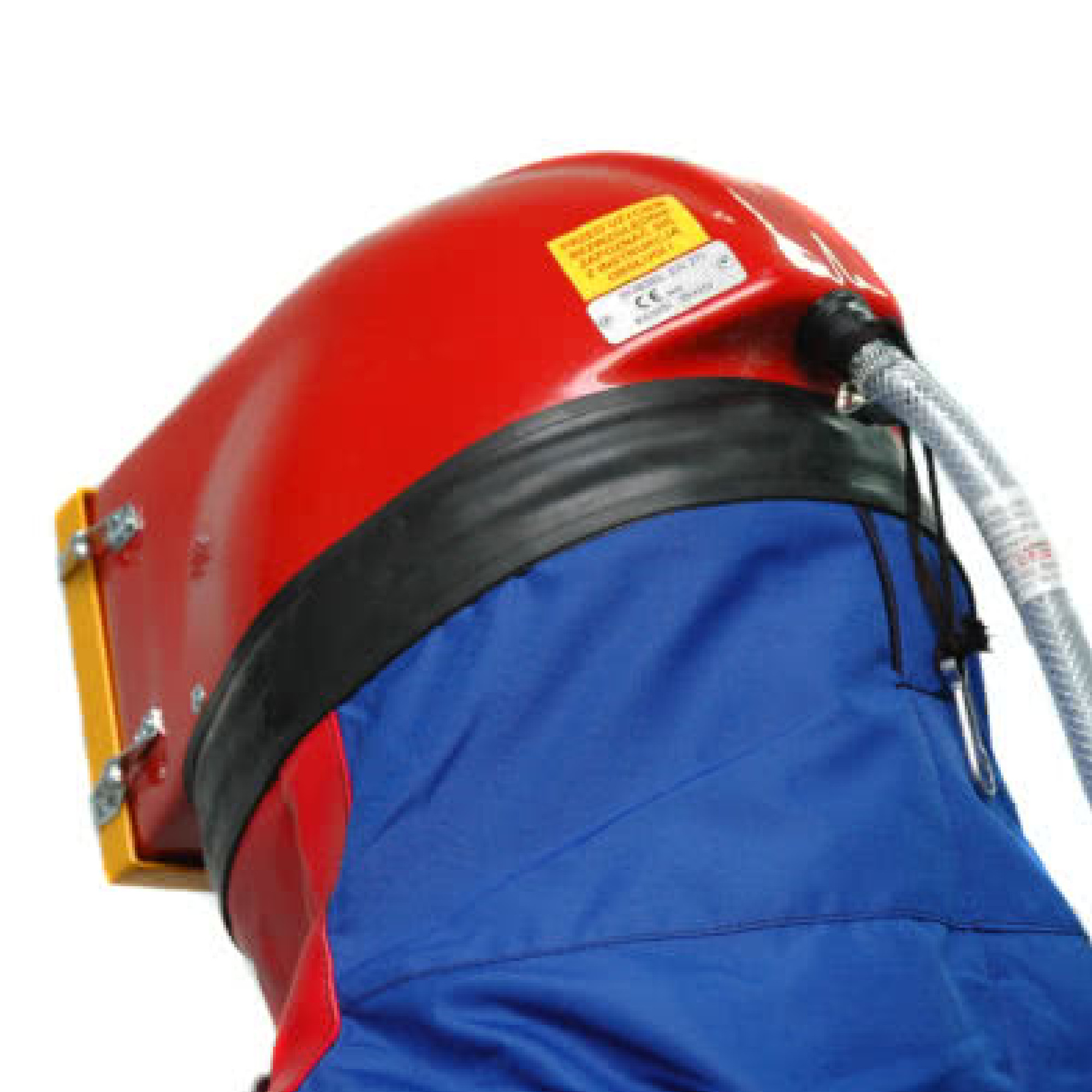 Ein Teil eines Schutzhelms in Rot mit einem blauen Anzug im Hintergrund. Der Helm hat eine klare Sichtschutzvorrichtung und einen Verbindungsschlauch. Ein gelbes Etikett mit Sicherheitshinweisen ist sichtbar.