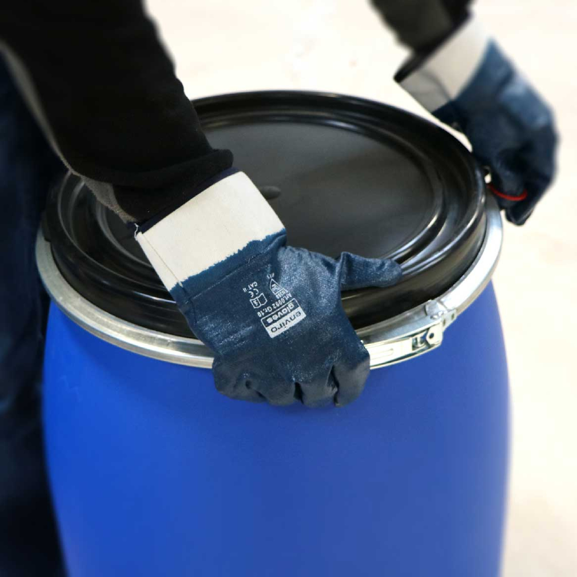 Anwendungsbild: Hände mit Enviro Gloves Nitrilhandschuhen öffnen Metallspannring eines blauen Kunststofffasses