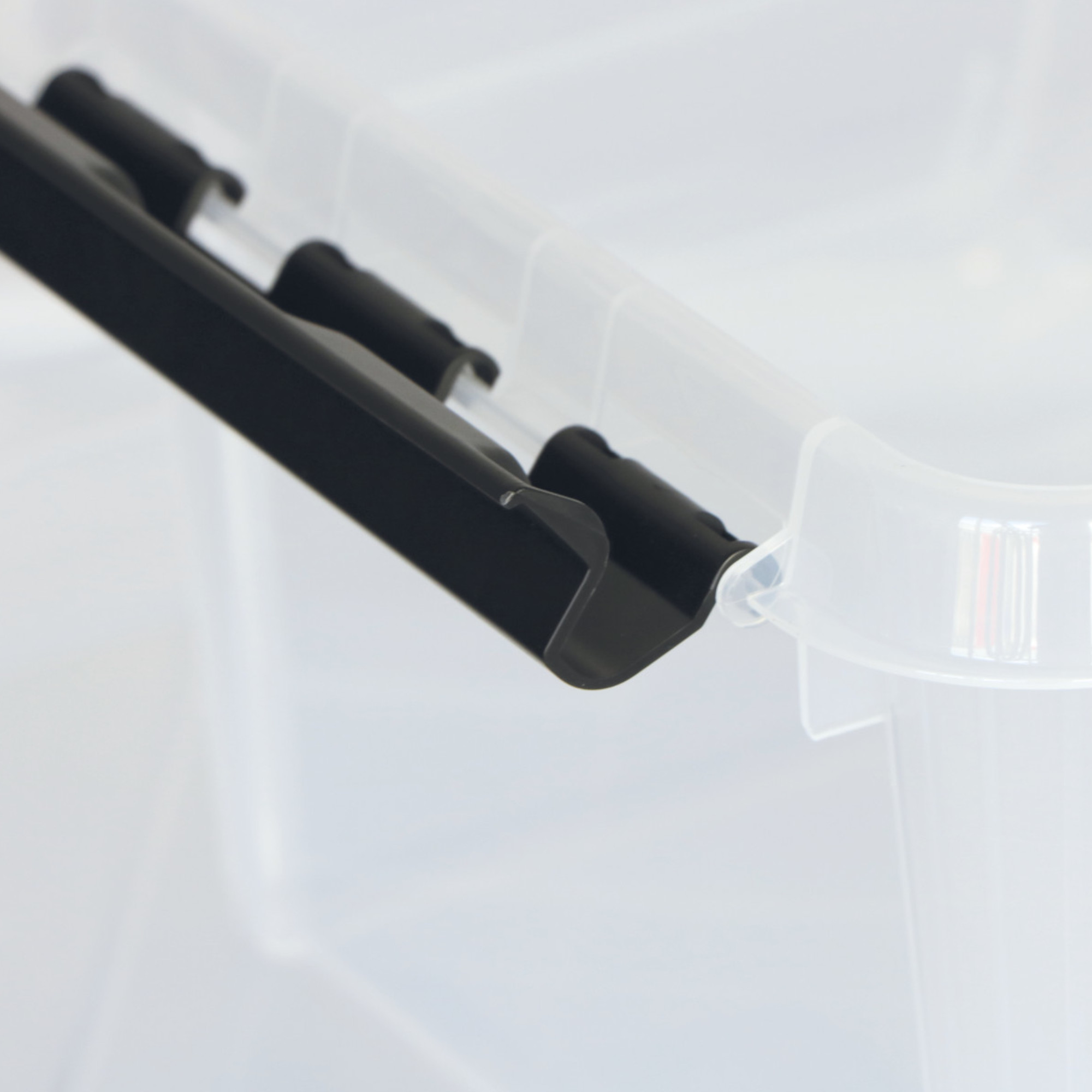 Ein transparenter Kunststoffbehälter mit einem schwarzen Clip-Verschluss an der Oberkante. Der Behälter ist geöffnet, und der Fokus liegt auf dem Verschlussmechanismus, der das sichere Schließen des Behälters ermöglicht.