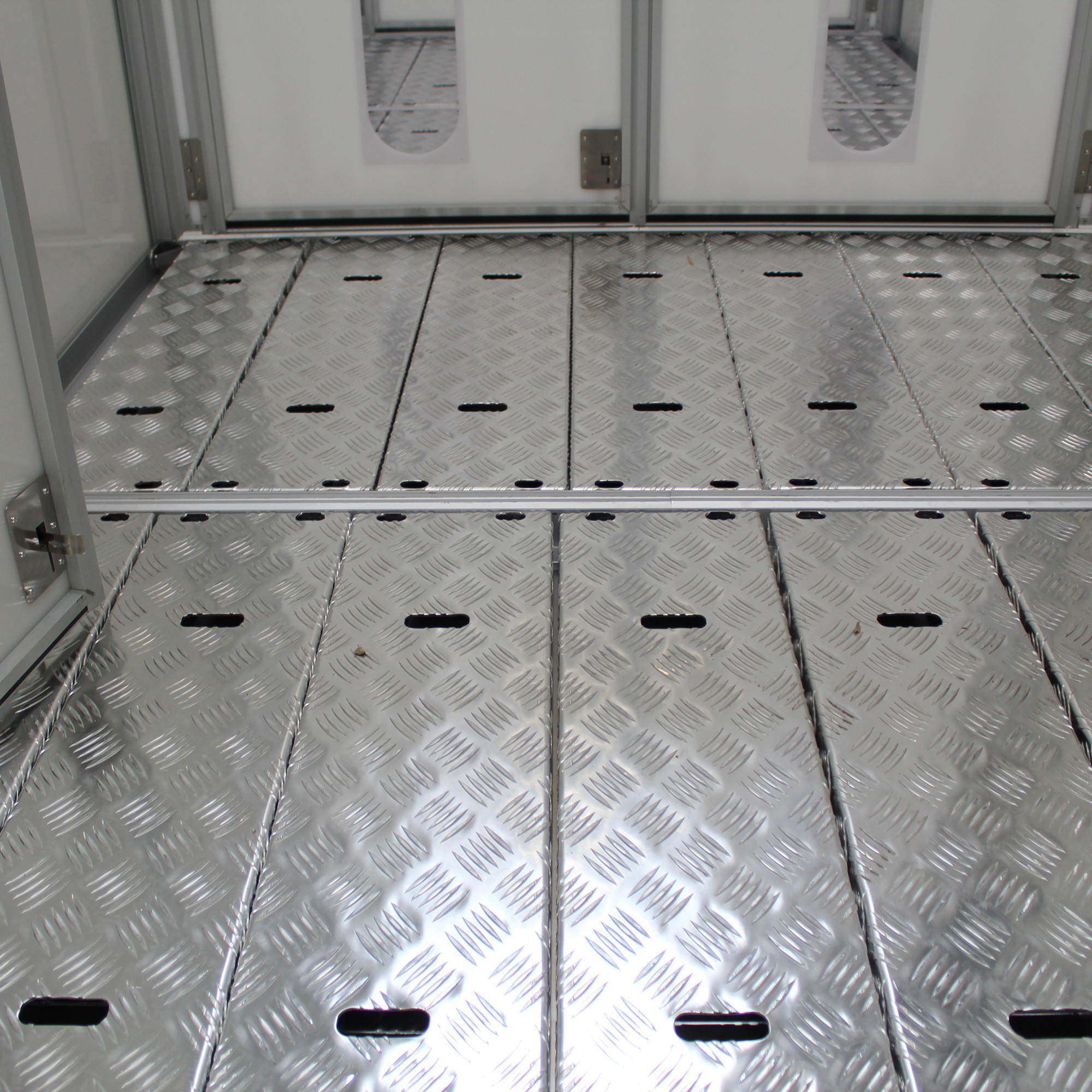 Rutschfester Aluminium-Boden mit Rautenmuster und Schlitzen in hellem Raum mit glatten, hellen Wänden